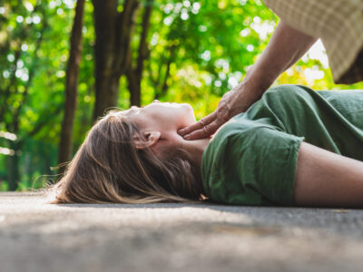 Unconscious fainted girl having pulse checked by an old woman